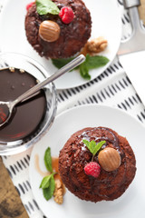 Plates with chocolate muffins and caramel topping on table