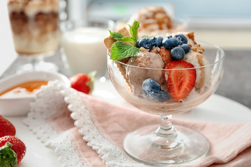 Bowl with ice cream, caramel, berries and nuts on table