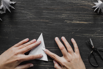 Three white paper Christmas trees with scissors on black wooden table
