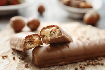 Tasty chocolate bars with caramel filling on parchment, closeup