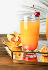 Glass with tasty exotic cocktail on tray