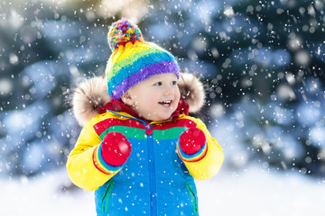 Child playing with snow in winter. Kids outdoors.