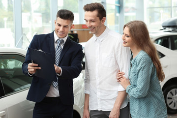 Young couple buying car in salon