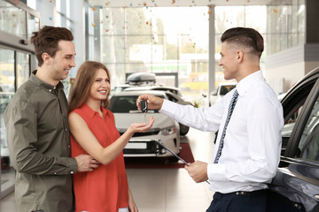 Young couple buying car in salon