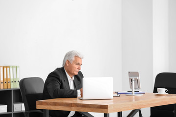 Senior man in formal suit working at desk in office