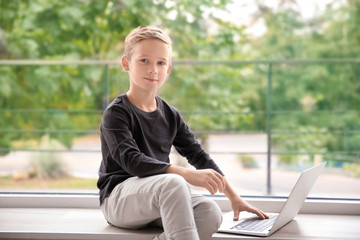 Cute little boy with laptop at home