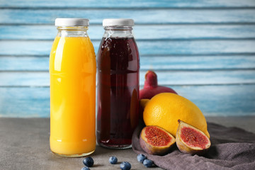 Bottles with fruit juices on table against blue wall