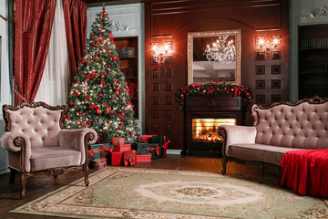 Christmas evening. classic apartments with a white fireplace, decorated tree, sofa, large windows and chandelier.
