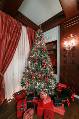 Christmas evening. classic apartments with a white fireplace, decorated tree, sofa, large windows and chandelier.