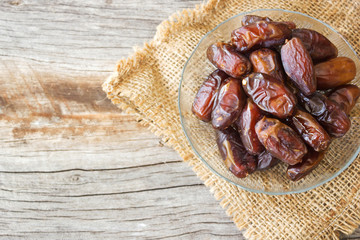Dried date fruit on glass plate over wooden table. Top view.