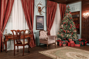 Christmas evening. classic apartments with a white fireplace, decorated tree, sofa, large windows and chandelier.