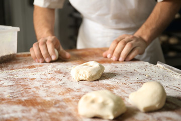 Man preparing buns at table in bakery