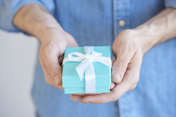 I want to give you a gift box. A man holding a present in his hands with wrapped with a bow.