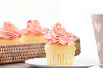Plate with delicious vanilla cupcake on table