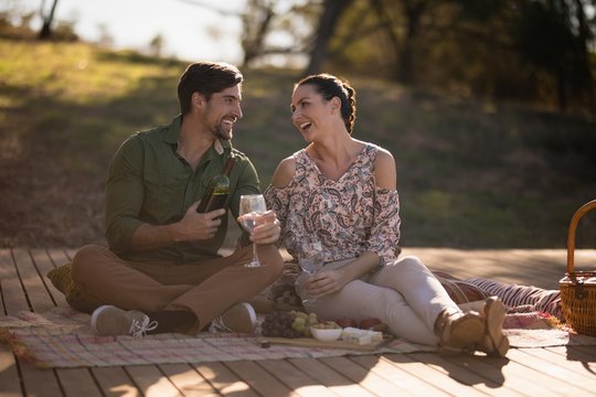 Couple having drinks together on wooden plank