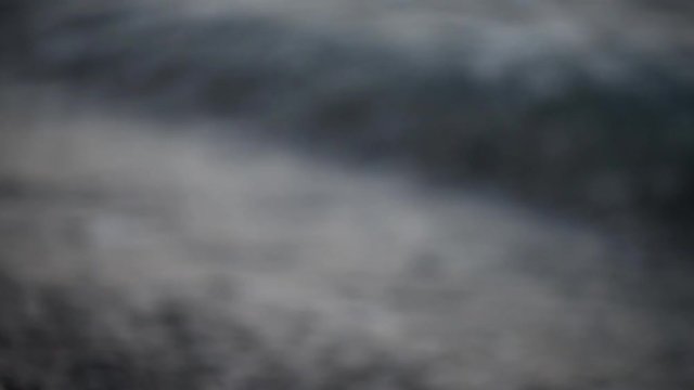 Particolare dell'onda che si infrange sulla battigia con piccoli sassi
