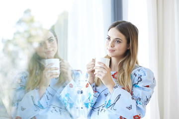 Smiling young woman having her morning tea at home