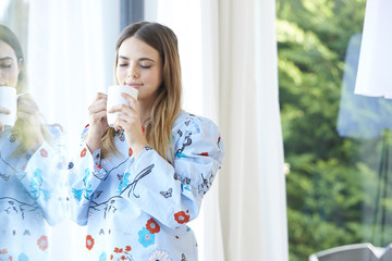 Smiling young woman having her morning tea at home