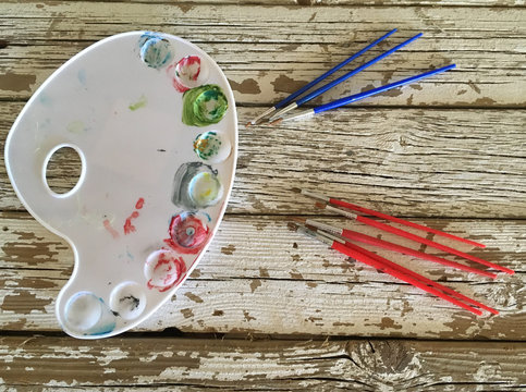 tavolozza colori e pennelli su sfondo legno con venrice bianca rovinata