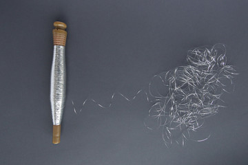 Silver thread pile like cloud and spool of silver thread. Reel or spool of silver thread on grey background.