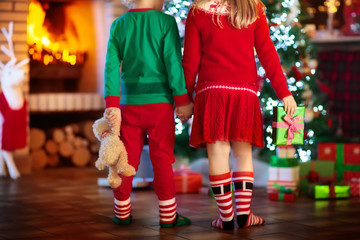 Obraz premium Child at Christmas tree. Kids at fireplace on Xmas