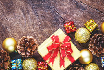 Christmas or New Year background with pine cones,gift box,golden ball of Xmas decorations and fir branches, flat lay, blank space for a greeting text on wooden board