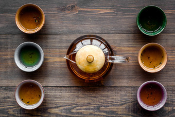 Set for tea ceremony. Glass teapot and ceramic cups on dark wooden background top view