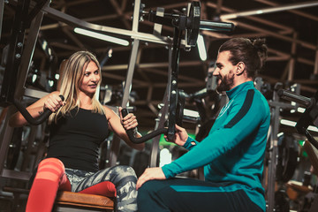 Fototapeta na wymiar Personal trainer giving weightlifting training to girl in gym