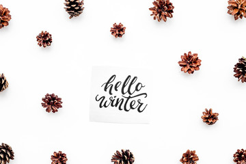 Fototapeta na wymiar Hello winter hand lettering. Winter pattern with pinecones on white background top view