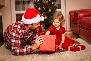 family, christmas, x-mas, happiness and people concept - smiling father and daughter in santa helper hats holding gift box