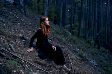 Naklejka na ściany i meble Beautiful young woman in a long dress lies in the forest, mountains, nature