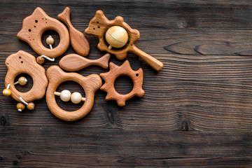 Cute wooden handmade toys for newborn on dark wooden background top view copyspace