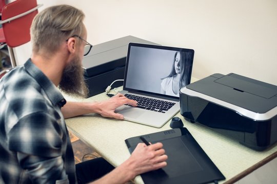 Photographer using graphics tablet while editing at table