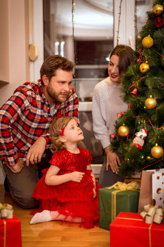 Happy family decorating a Christmas tree with boubles in the living-room