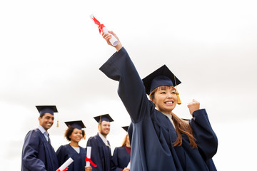 happy students in mortar boards with diplomas