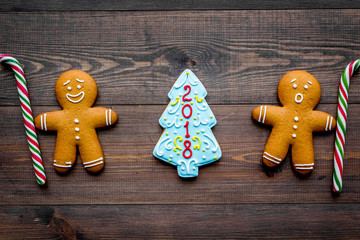 Cookies for New Year. Gingerbread man and spruce with lettering 2018 on wooden background top view