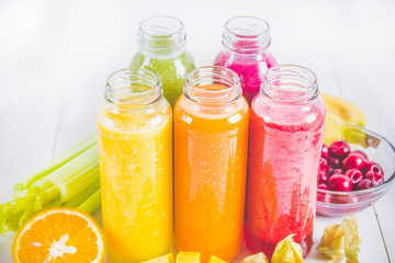 Multicolored smoothies in bottles of mango, orange, banana, celery, berries, on a wooden table.