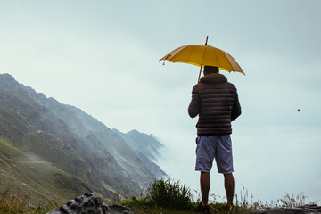 Man in the mountains, with a yellow umbrella