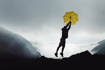 Obraz premium Man in the mountains, with a yellow umbrella