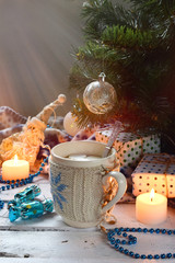 Christmas and new year holiday celebration concept background. Cup of cocoa with marshmallow, homemade chocolate cookie and peanut biscuit, lighted candles, xmas tree decoration on wooden table.