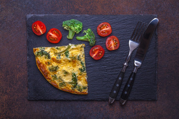 Omelette with broccoli on a black slate, horizontally