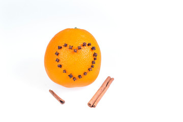 Fresh juicy bright orange decorated with a heart of cloves and vanilla sticks on a white background.