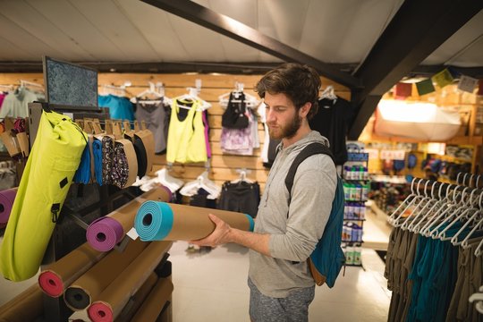 Man examining exercise mats in store