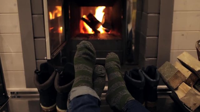 the feet of a young couple in warm socks near the fireplace