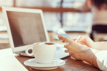 the girl works in a cafe for a laptop and drinks coffee
