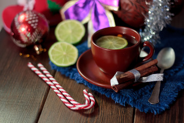 Christmas tea on wooden table with lime and candy canes.
