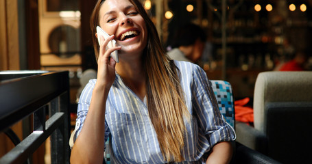 Beautiful woman talking on phone in restaurant