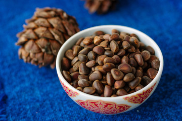 Fresh and ripe pine or cedar nuts in a bowl over blue background.