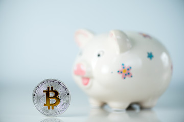 White piggy bank or money box with money coins - Bitcoin, the most popular cryptocurrency and virtual money. Investition and savings concept