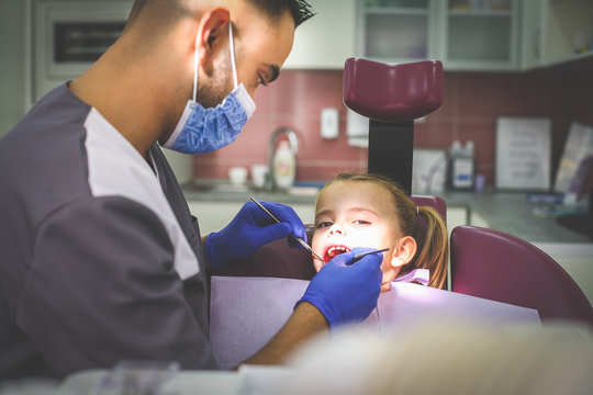 Young male dentist examining little girl.